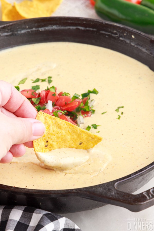 Bowl of queso blanco with chip dipped in it.