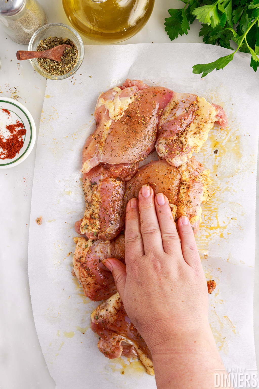 Hand rubbing spices into raw boneless skinless chicken thighs.