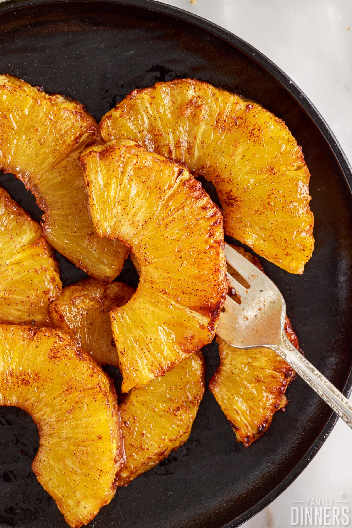 cooked pineapple on a plate with a fork