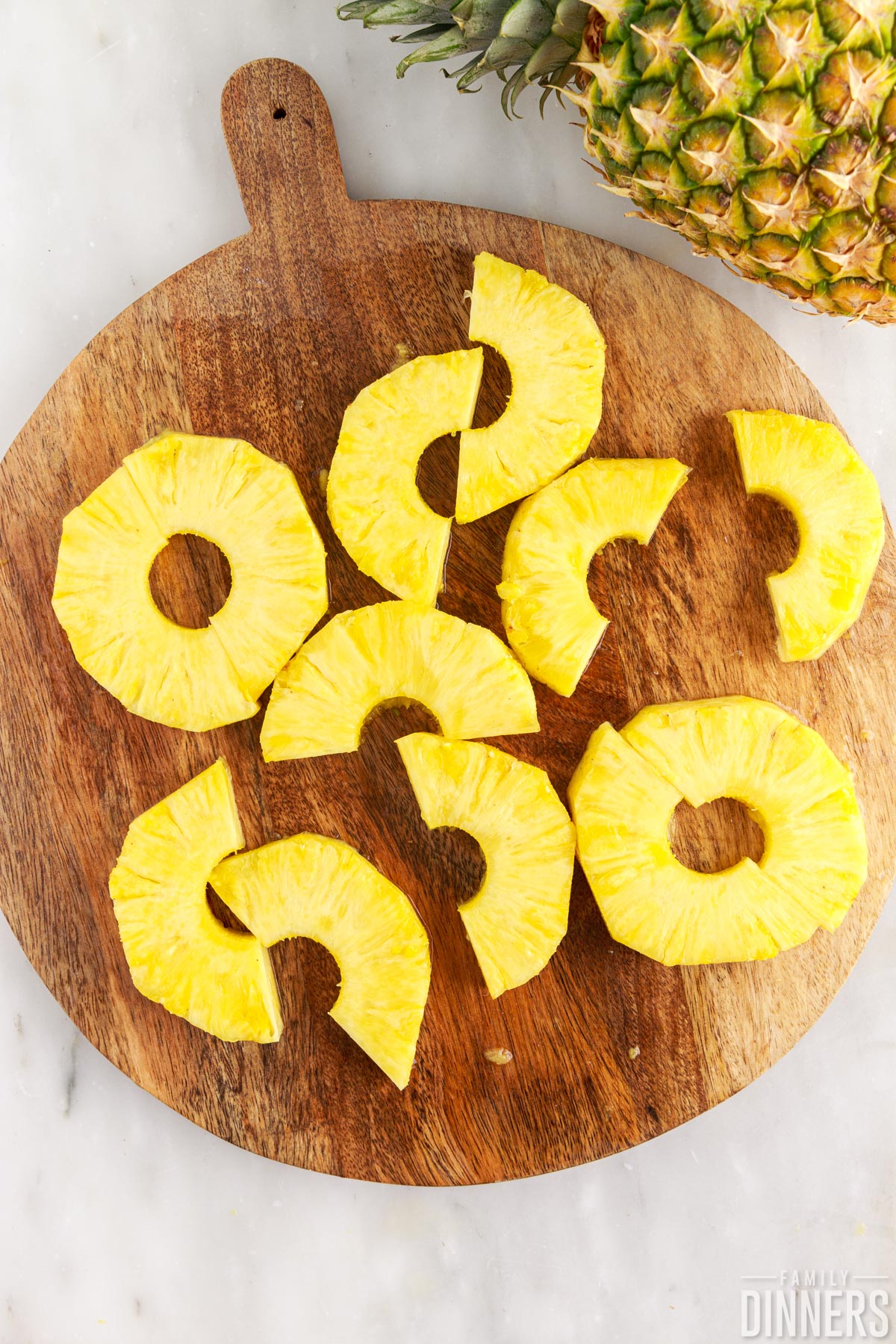 Sliced pineapple rings on a cutting board.