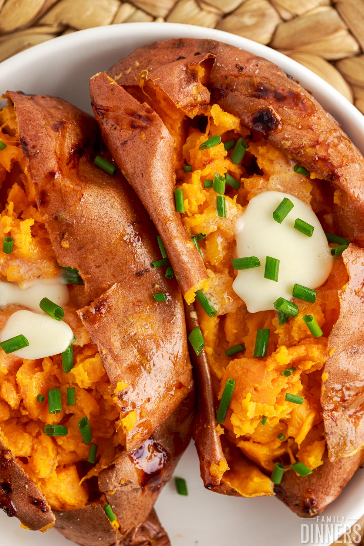 air fryer sweet potatoes on a plate topped with butter and chives
