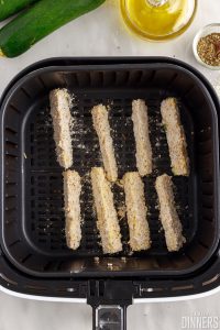 Uncooked zucchini fries in an air fryer.