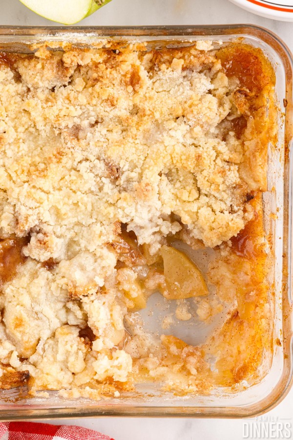 Pan of apple crisp without oats with a scoop out.