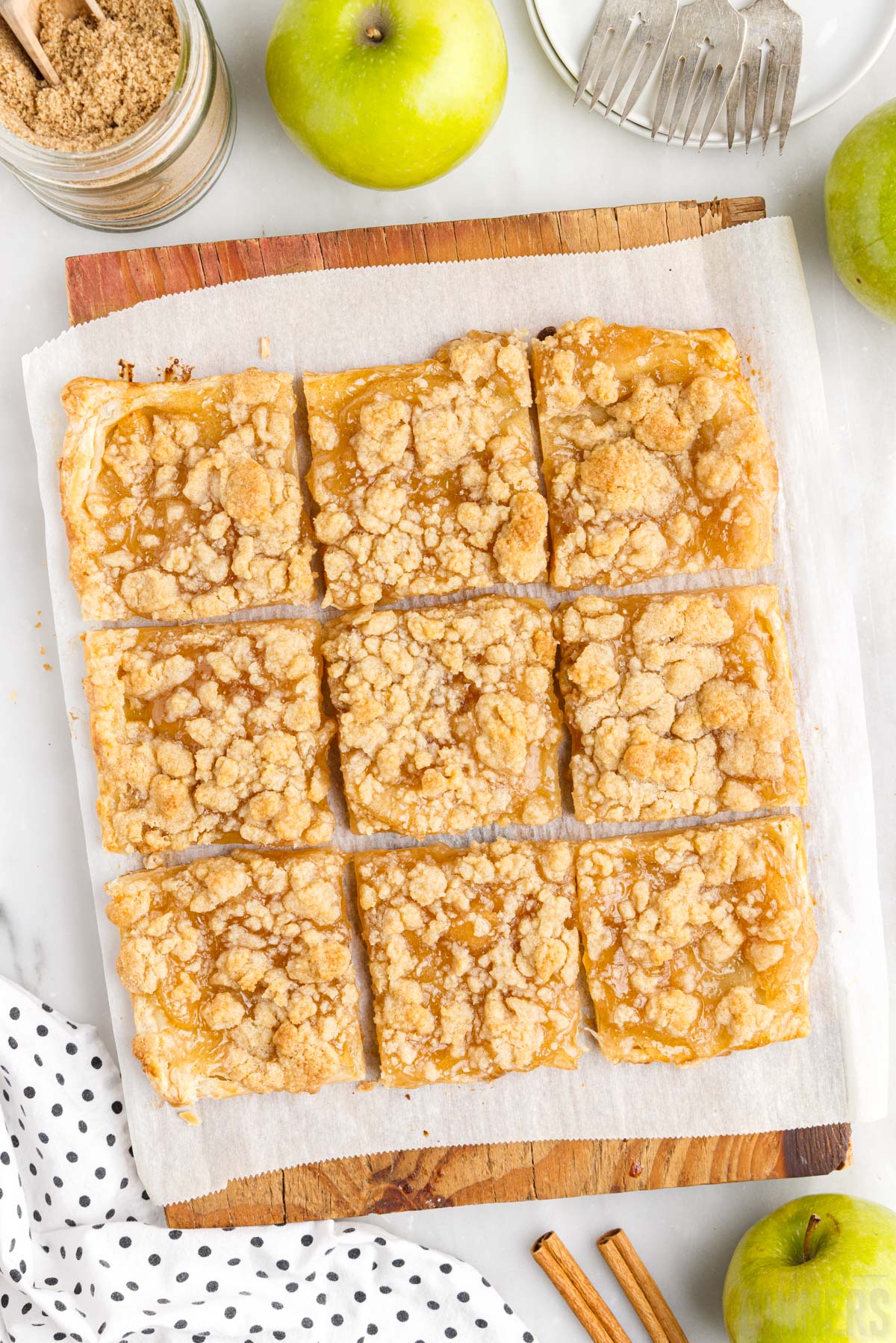 apple pie bars on a cutting board with fresh apples