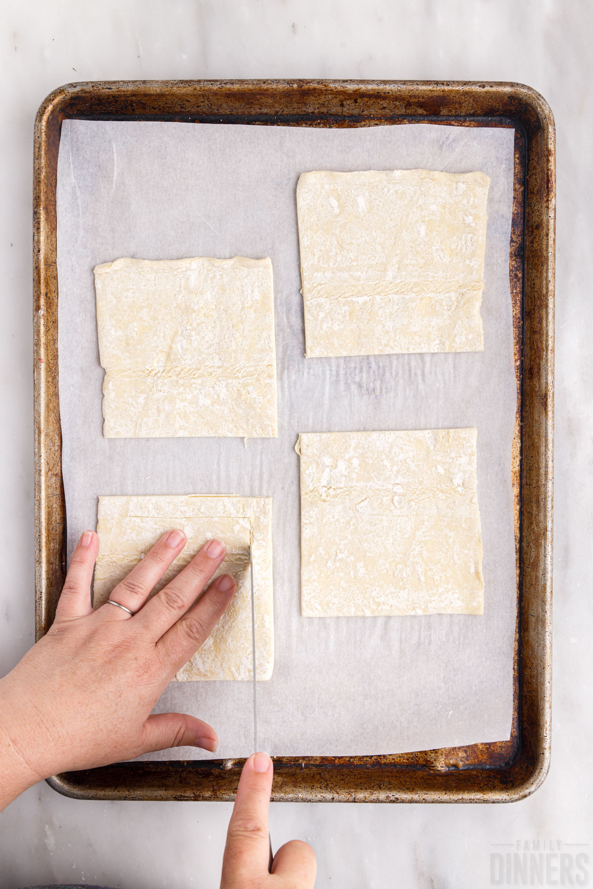 using a knife to score the puff pastry squares