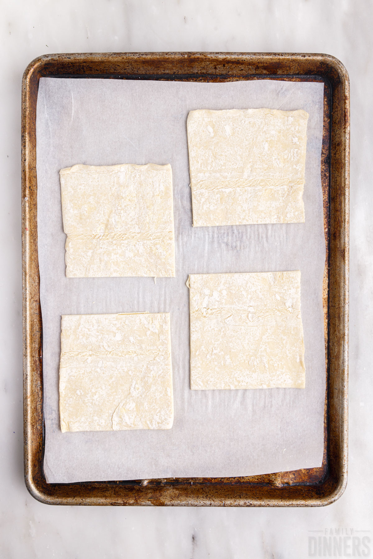 four puff pastry squares on a baking sheet