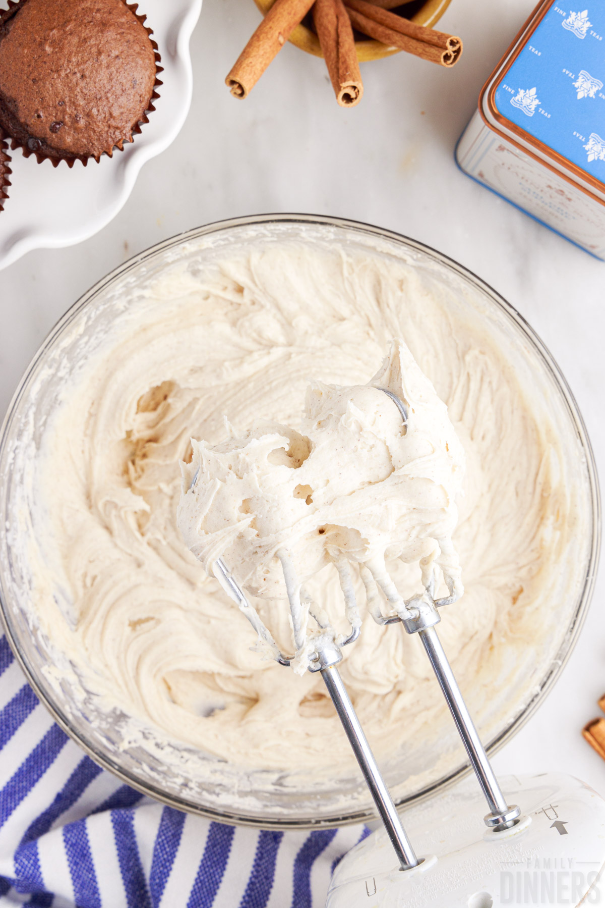 cinnamon cream cheese frosting in a bowl with whisks