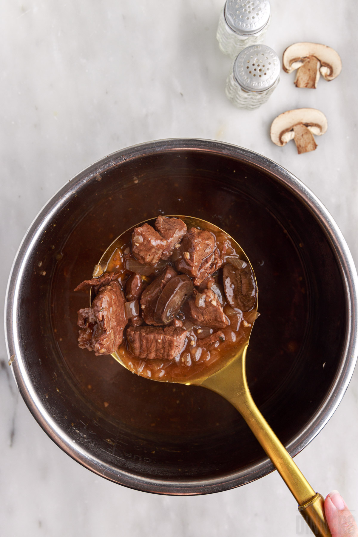 Instant Pot beef tips on a serving spoon over Instant Pot.