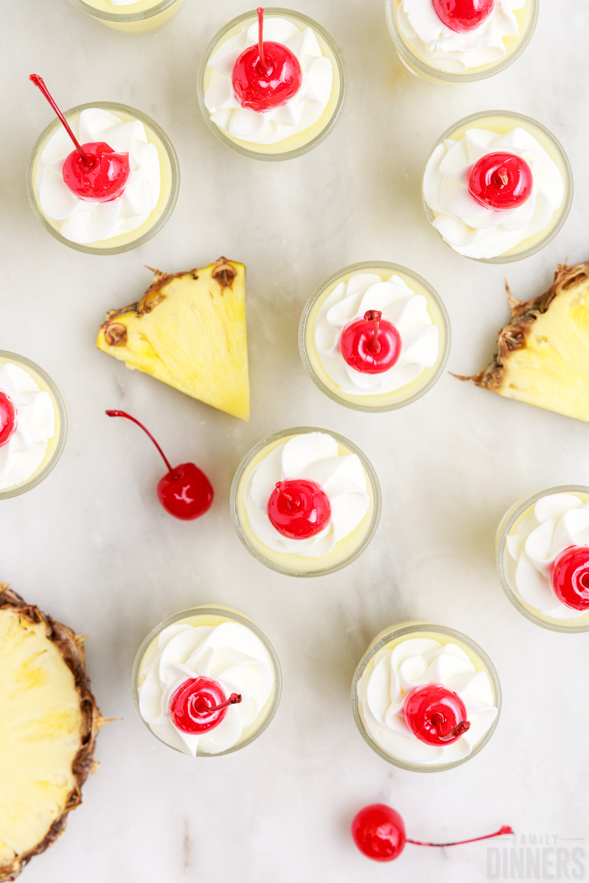 tops of pineapple jello shots with whipped cream and a maraschino cherry