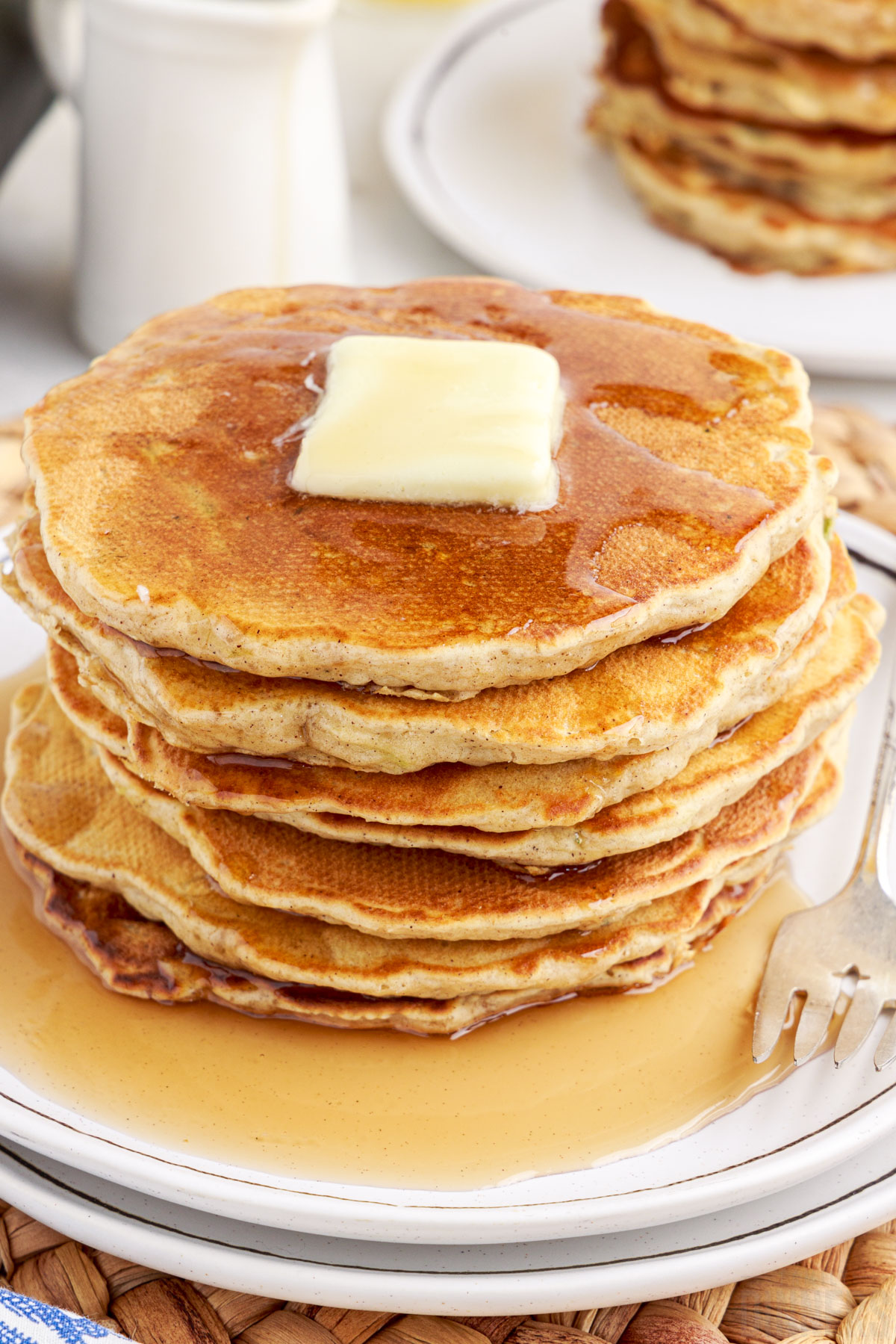 stack of pancakes on a plate with syrup and butter