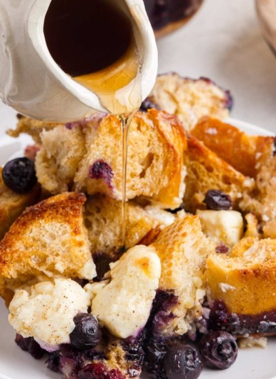 blueberry french toast casserole with syrup being poured on top.