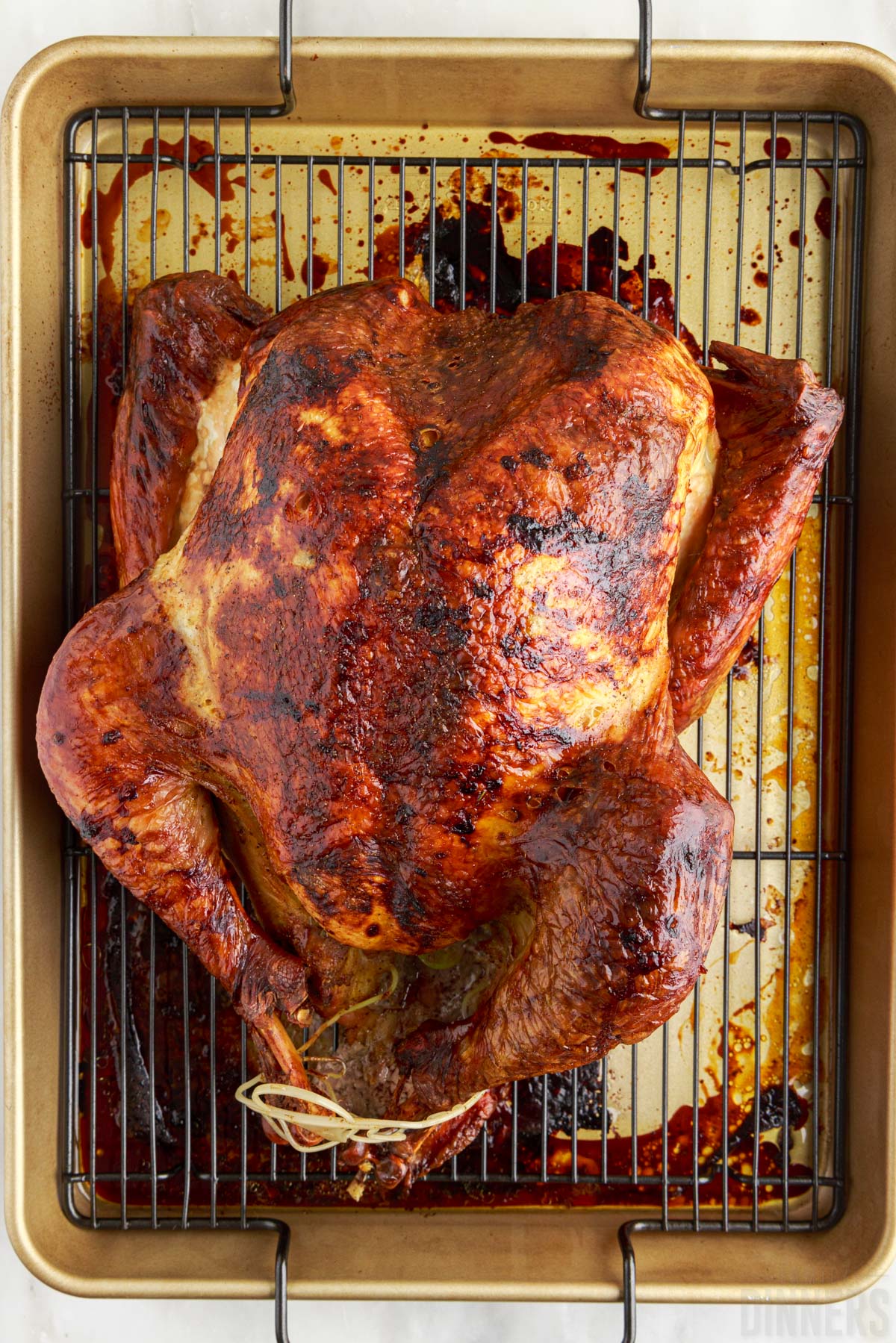 cooked turkey on a baking rack over a baking sheet