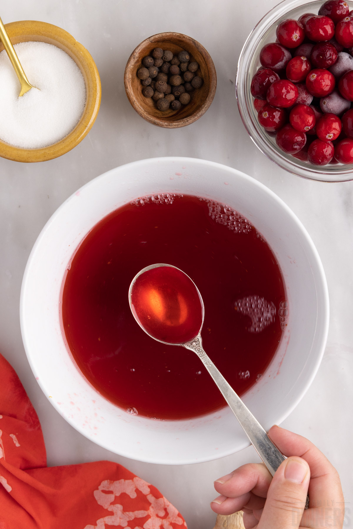 finished cranberry simple syrup in a bowl with a spoon