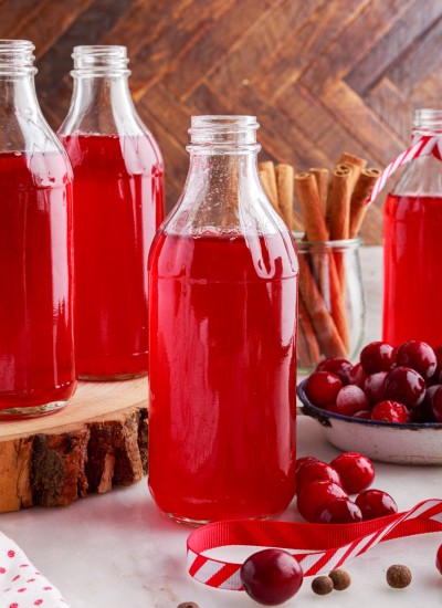 cranberry simple syrup bottles with fresh cranberries and cinnamon sticks