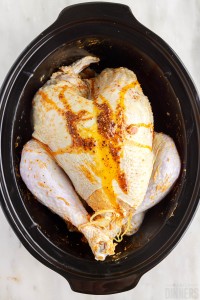spice mix drizzled over raw turkey in the slow cooker