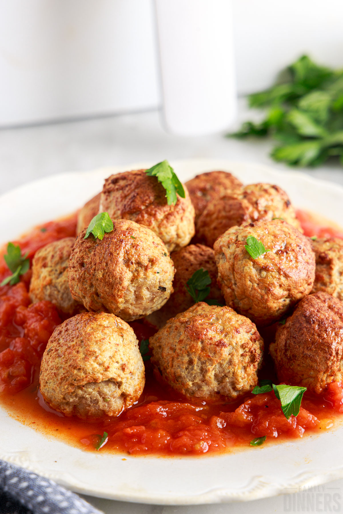 meatballs with marinara on a plate with fresh parsley sprinkled on top