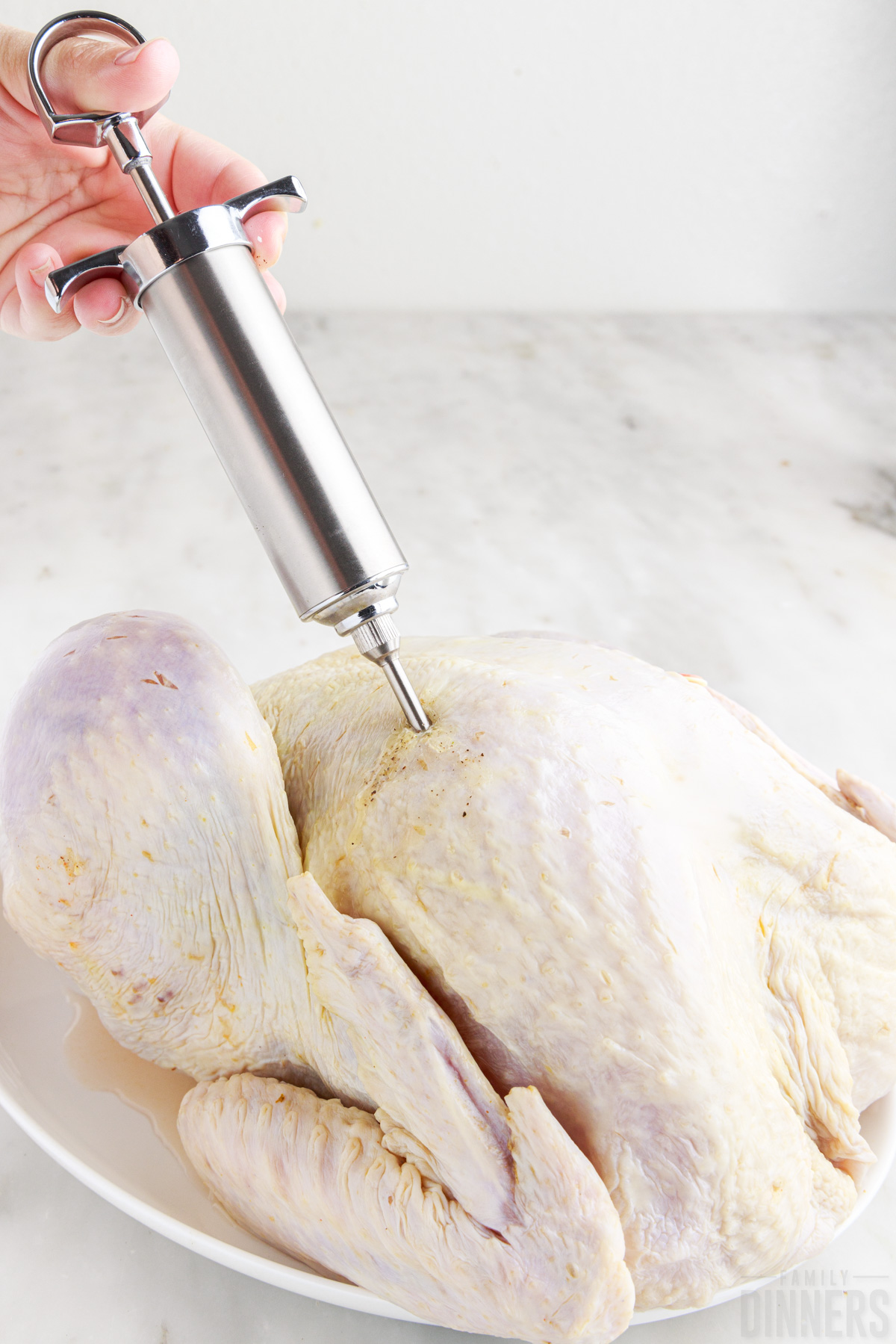 injecting lemon butter mixture into chicken