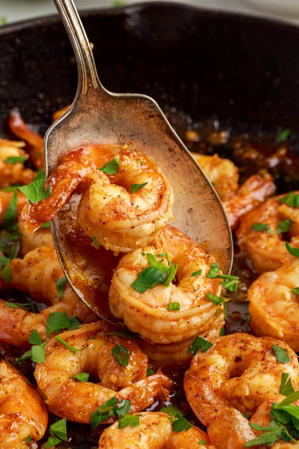 spoon scooping honey lime shrimp sprinkled with parsley