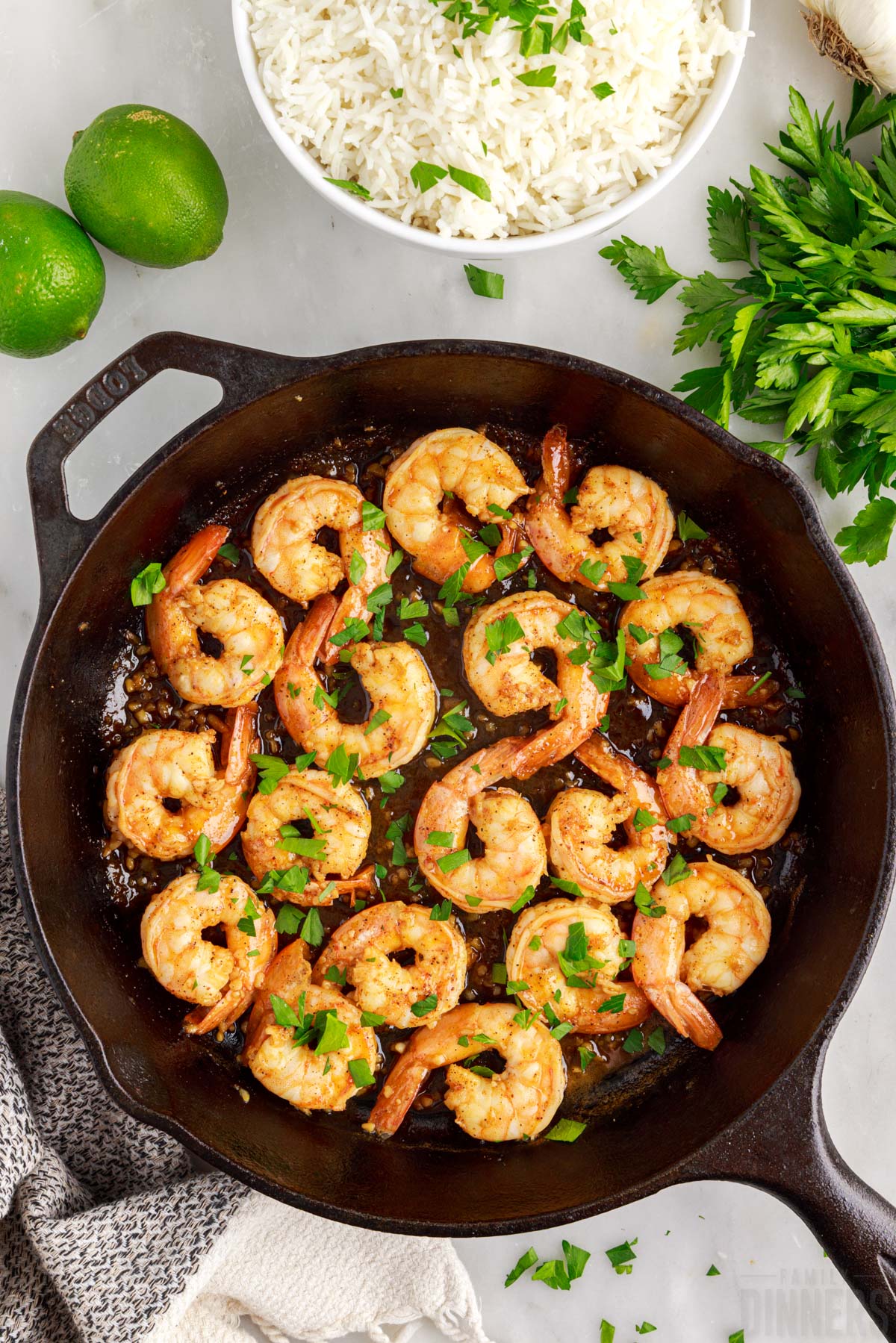 skillet with honey lime shrimp with rice and limes next to it