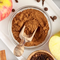 glass bowl of apple pie seasoning with a wooden spoon