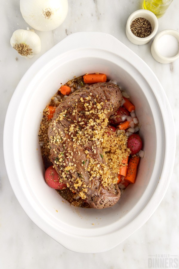 seared roast on top of vegetables in the slow cooker
