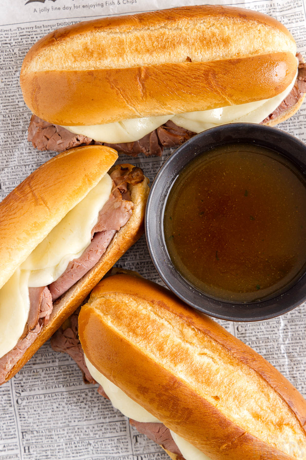 french dip sandwiches with au jus dipping sauce on a piece of paper