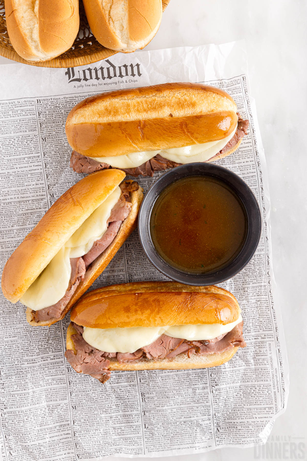French dip sandwiches with au jus gravy on a piece of paper