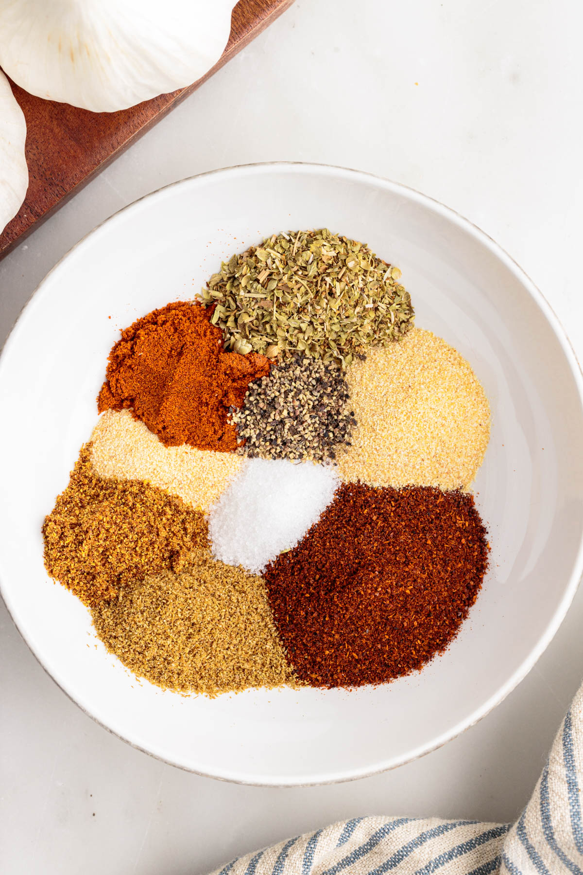 ingredients for taco seasoning in a white bowl, unmixed