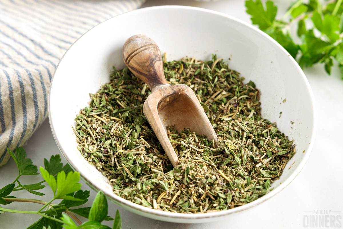 white bowl full of Italian seasoning with a wooden spoon