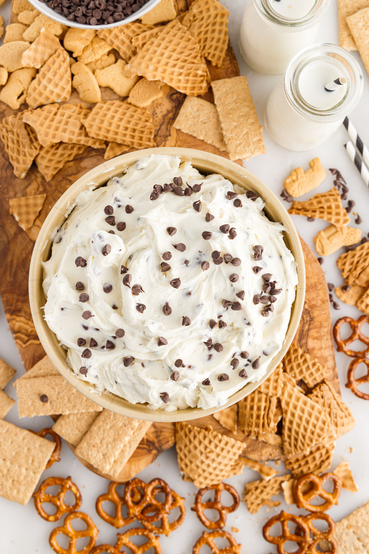 bird's eye view of a bowl of cannoli dip topped with chocolate chips and surrounded by crackers and pretzels