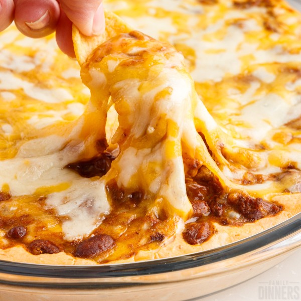 Chip pulling up cheese on chili cheese dip.