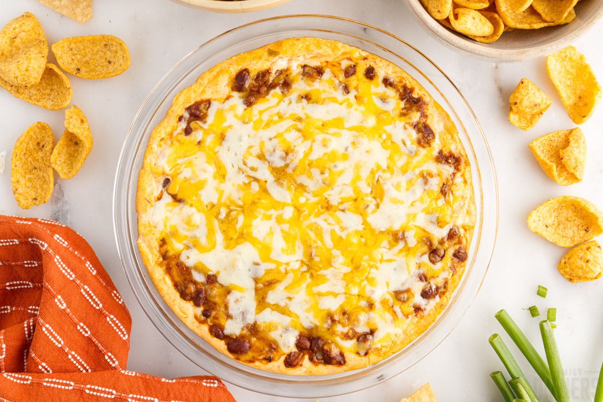 bird's eye view of a bowl of chili cheese dip with chips around it