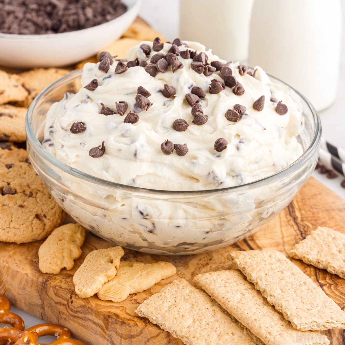 glass bowl full of cookie dough dip with dippers around it
