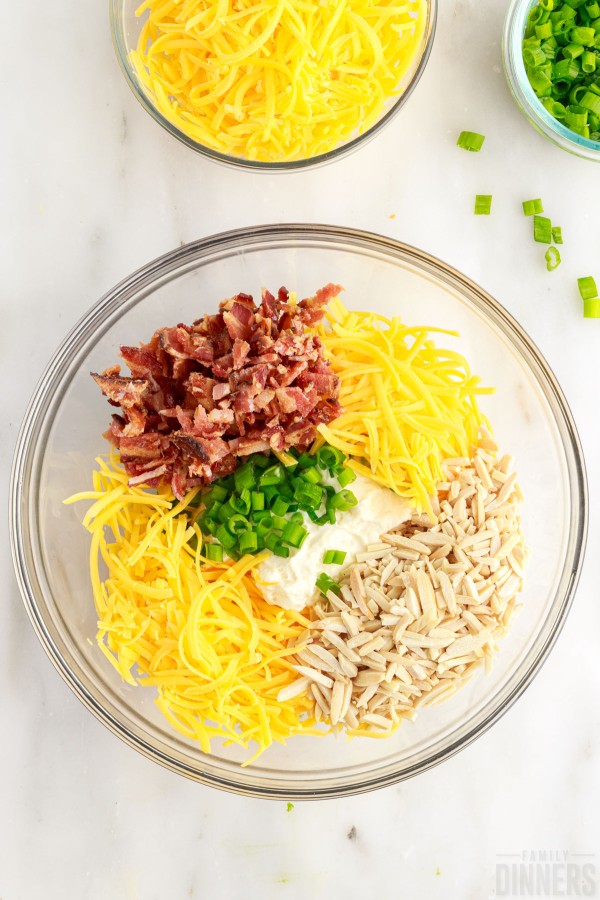 mayonnaise, cheese, green onions, almonds and bacon in a mixing bowl
