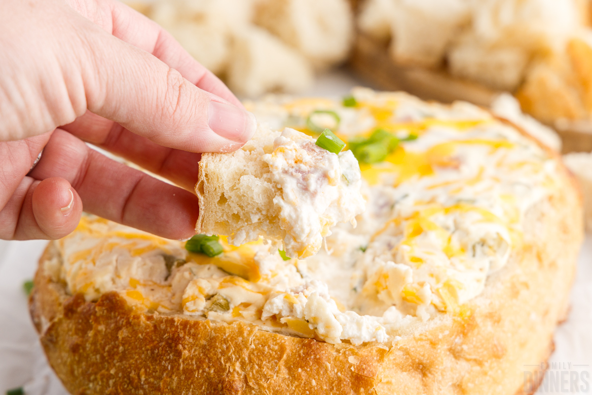 hand dipping a bread cube into hot Mississippi sin dip