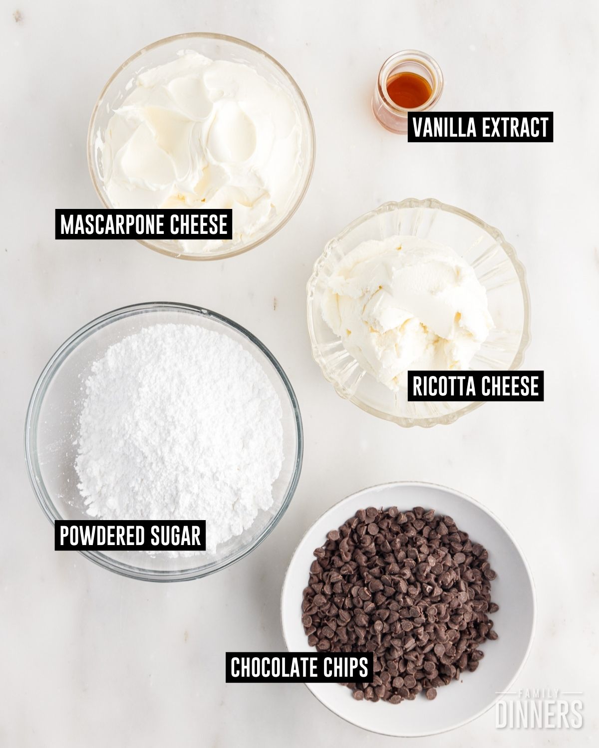 Bowls of vanilla extract, mascarpone cheese, ricotta cheese, powdered sugar and mini chocolate chips.