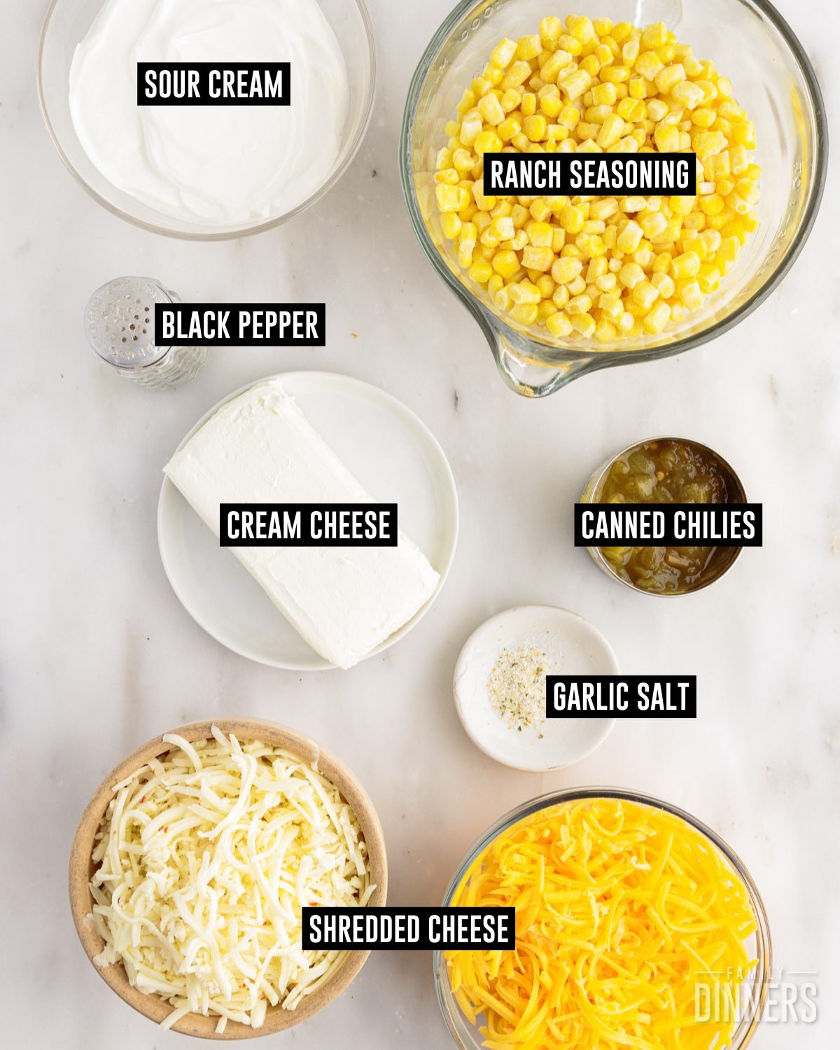 Crack corn dip ingredients in bowls: corn, sour cream, cream cheese, canned green chilies, shredded cheese, garlic salt and black pepper.