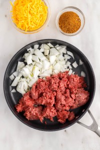 raw ground beef and chopped onions in a skillet