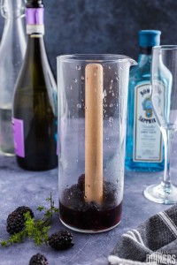 muddler in a glass with blackberries
